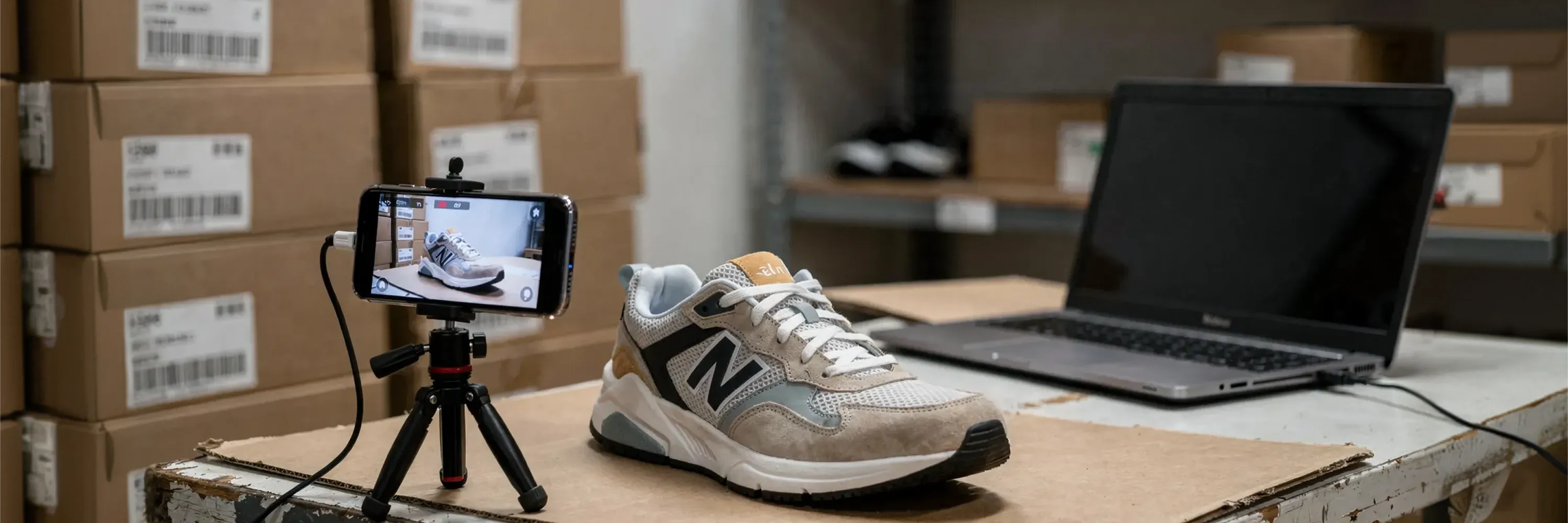 A sneaker is photographed and recorded with a smartphone on a tripod in a warehouse setting, illustrating e-commerce product content creation and online retail workflows